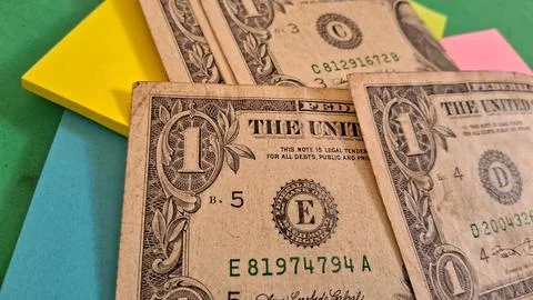 Multiple one dollar bills resting on bright colorful office sticky notes Stock Photos
