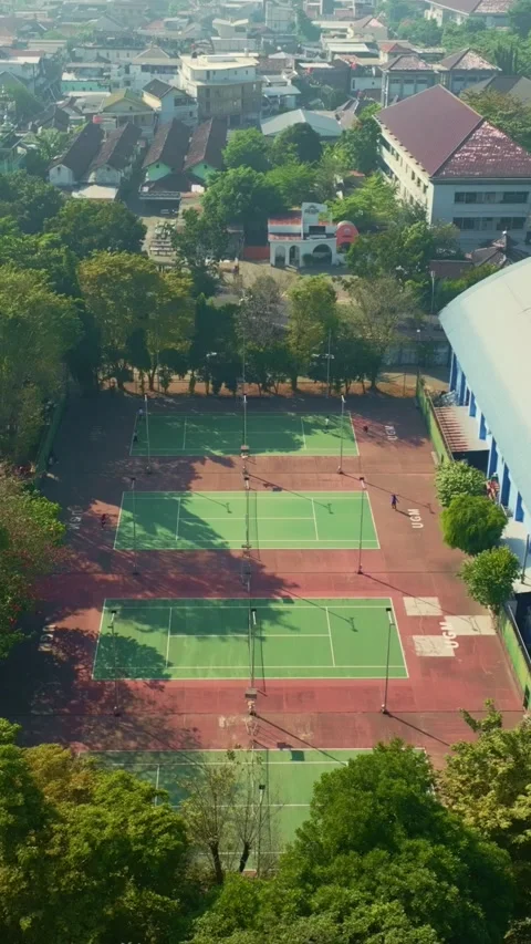Multiple outdoor tennis courts surrounded by lush trees in Yogyakarta Stock Footage 342589651