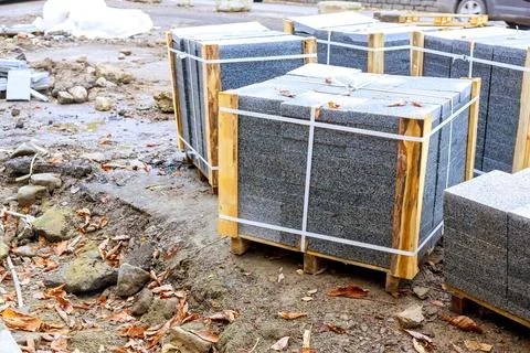 Multiple pallets of gray granite paving stones at construction site Stock Photos