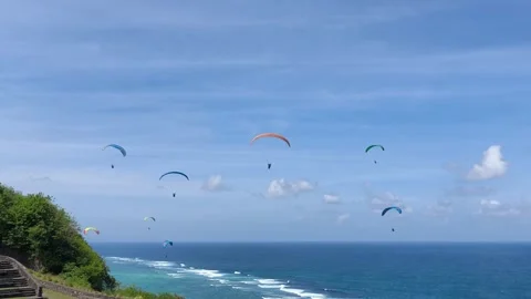 Multiple Paragliders Soaring High Over a Beautiful Tropical Coastline and Ocean Stock Footage 340157480