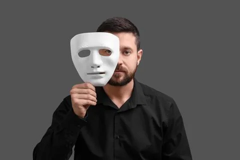 Multiple personality concept. Man covering face with mask on grey background Stock Photos
