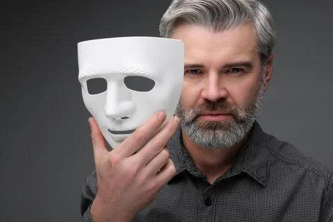 Multiple personality concept. Man with mask on dark grey background Stock Photos