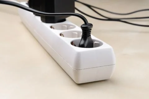 Multiple plugs are plugged into the splitter outlet. Stock Photos