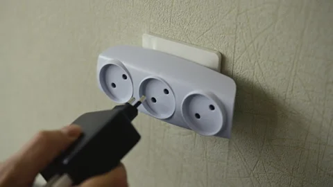 Multiple plugs overloading wall socket with tee adapter, increasing risk of Stock Footage 312722097