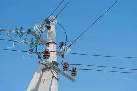 Multiple power lines converging on concrete pole with interconnected insulators Stock Photos