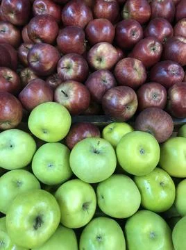 Multiple red and green apples for sale at an outdoor market. Stock Photos