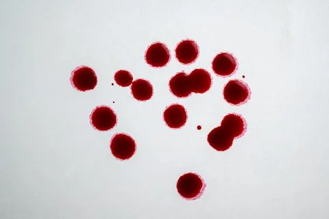Multiple red blood droplets and splatters on a textured light gray backgrou.. Stock Photos