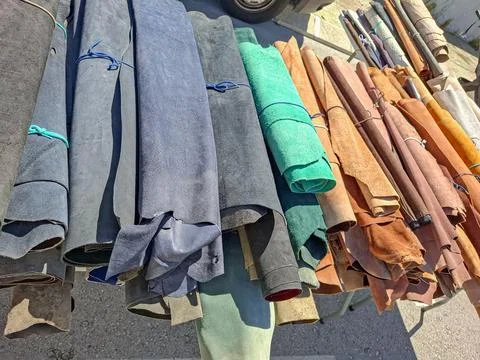 Multiple rolls of colored suede and leather are arranged for sale in a sunn.. Fotos Stock