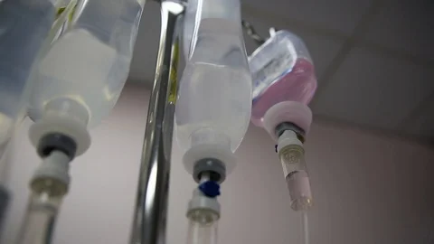 Multiple saline solution bottles hanging from pole inside a hospital. Stock Footage 94038670