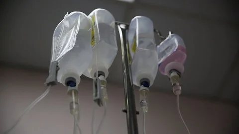 Multiple saline solution bottles hanging from pole inside a hospital. Stock Footage 94038672