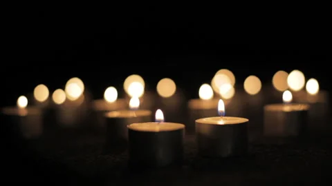 Multiple short decorative candles burning in darkness Stock Footage 233473367