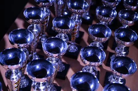 Multiple Silver Trophy Cups in Blue Spotlight Lighting Stock Photos