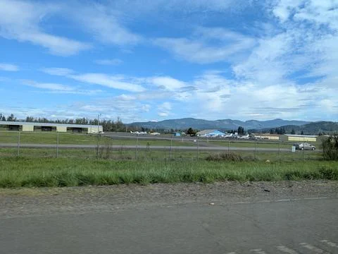 Multiple small airplanes lined beside private hangars near a highway Stock Photos