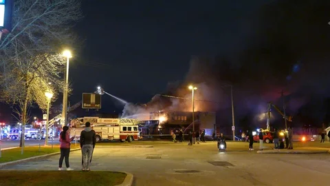 Multiple small groups of people gathered in parking lot to watch fire Stock Footage 129986951