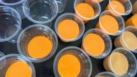 Multiple small plastic cups filled with vibrant orange and creamy yellow Stock Photos