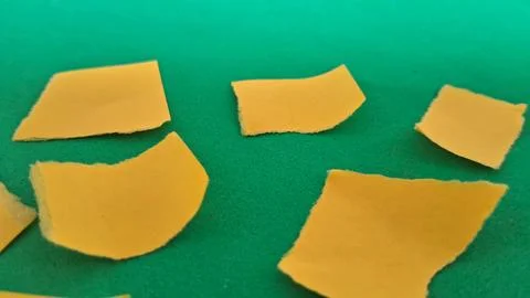 Multiple small yellow paper squares scattered on a bright green background Fotos de archivo