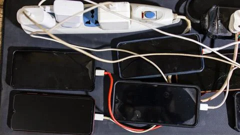 Multiple Smartphones Charging Simultaneously On Power Strips With Tangled C.. Stock Photos