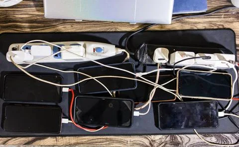 Multiple Smartphones Charging Simultaneously With USB Cables on Desktop Wor.. Stock Photos