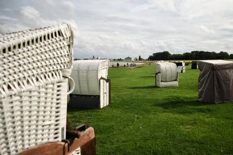 Multiple strandkorb woven chairs overlooking the bay on a sunny summer day Stock Photos