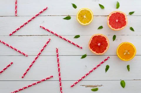 Multiple straws arranged along with cut citruses and mint leafs on a white Stock Photos