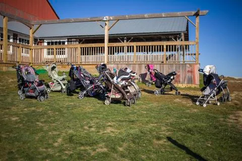 Multiple strollers in field with building behind Stock Photos
