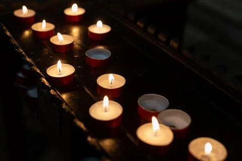 Multiple Tealight Candles Burning in Darkness Foto stock
