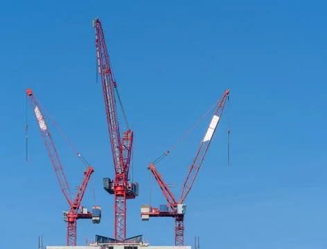 Multiple tower cranes above a concrete structure. Stock Photos