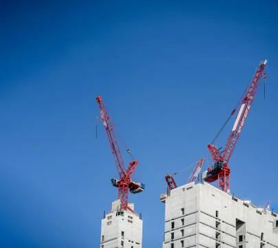Multiple tower cranes above a concrete structure. Stock Photos
