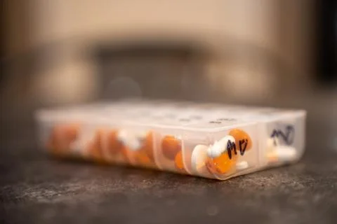 Multiple types of pills in a daily container with days of the week. Stock Photos