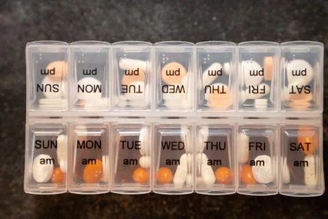 Multiple types of pills in a daily container with marked days of the week on Stock Photos