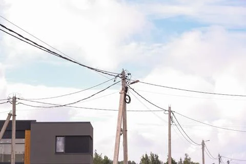 Multiple utility poles with power lines and street lights against a cloudy sk Stock Photos