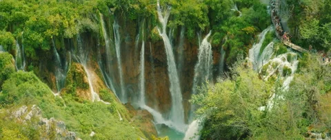 Multiple waterfalls cascading into turquoise lake while crowd of tourists on Video stock 313016365