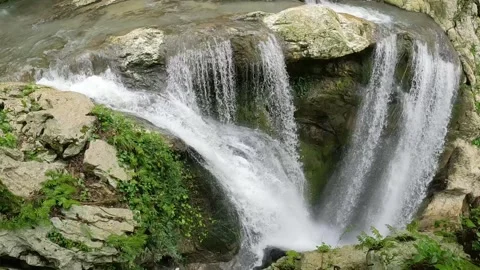 Multiple waterfalls flowing over rocks in lush green forest Stock Footage 312198297