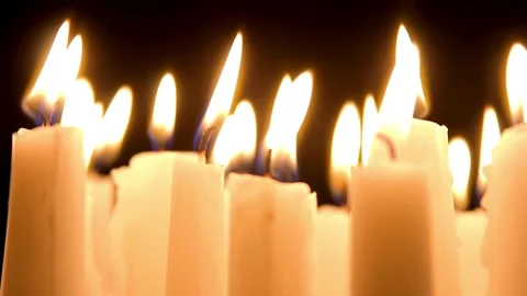 Multiple white candles burning brightly in a dark room Vídeo Stock 333836180