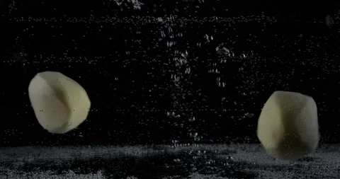 Multiple white peeled potatoes dropped falling in water with lot of splashes Stock Footage 148750616