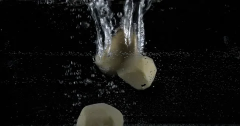 Multiple white peeled potatoes dropped falling in water with lot of splashes Video stock 148750881