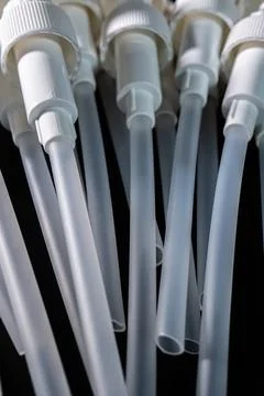 Multiple white plastic pump dispensers with long transparent tubes arranged.. Stock Photos