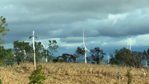 Multiple wind generators appear beyond trees and farmland, partially blurred by Stock Footage 329615920