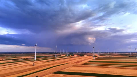 Multiple wind turbines operating across striped agricultural fields. Wide aerial Stock Footage 339015949