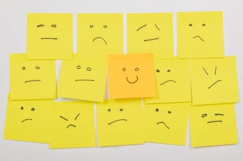 Multiple Yellow Sticky Notes with Hand-Drawn Faces Showing Mixed Emotions Stock Photos