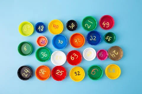 Multiplication problems on colorful bottle caps arranged on blue background.. Stock Photos