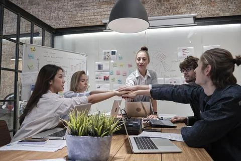 Multiracial colleagues teamwork joining hands together in a meeting room. Stock Photos