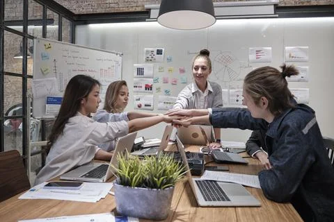 Multiracial colleagues teamwork joining hands together in a meeting room. Stock Photos