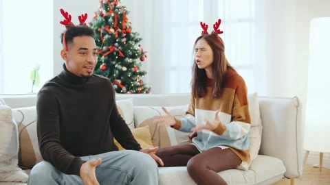 Multiracial couple having a serious conversation near Christmas tree while Stock Footage 319969092