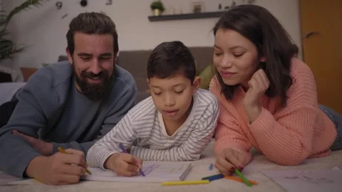 Multiracial couple with young son doing homework at home. Cozy living room with Stock Footage 253677482