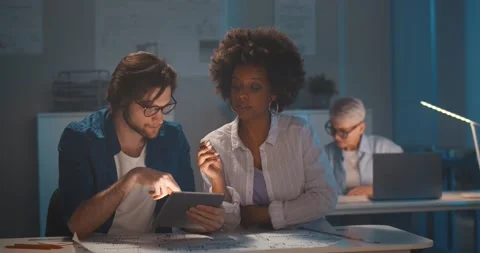 Multiracial engineer team working in dark office with tablet pc and blueprint Stock Footage 154149822