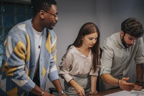 Multiracial executives discuss blueprints in a collaborative boardroom meeting Stock Photos