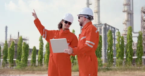 Multiracial female engineer points toward refinery tower while male supervisor Stock Footage 339650416