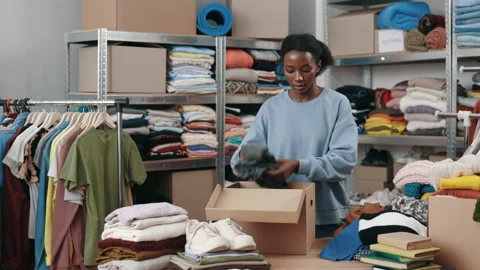 Multiracial female worker folding clothes and putting it into the cupboard box Stock Footage 226217485