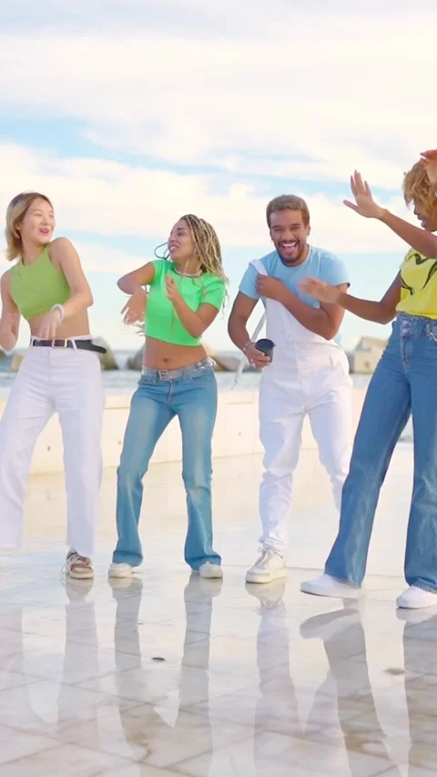 Multiracial friends dancing happily together next tot he sea Stock Footage 264374576